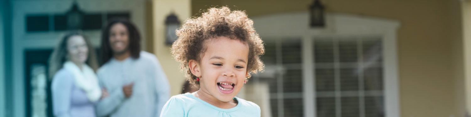 Little girl running in front of house