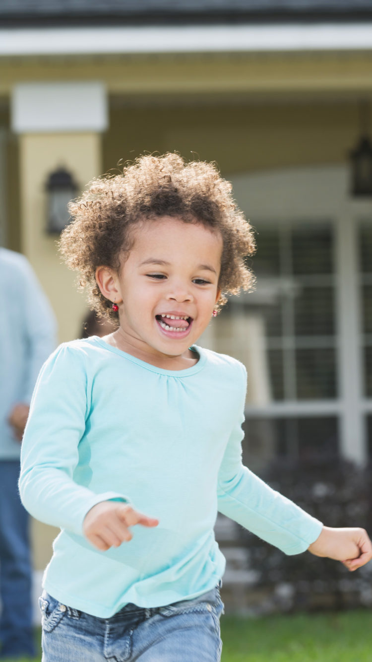 Little girl running in front of house